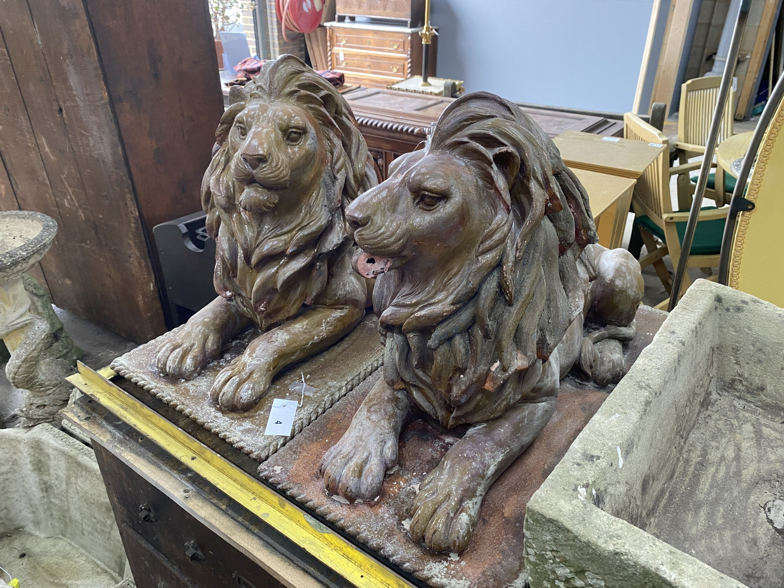 A pair of faux terracotta resin recumbent lion garden ornaments, length 74cm, width 36cm, height 50cm